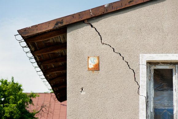 Imagem de uma parece rachada logo abaixo da estrutura do telhado.